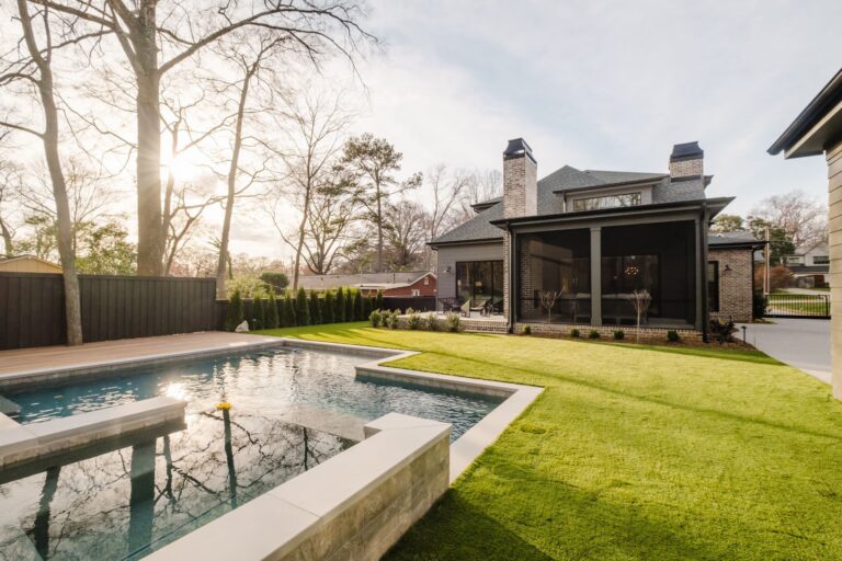 Custom backyard pool beside a screened porch and green lawn